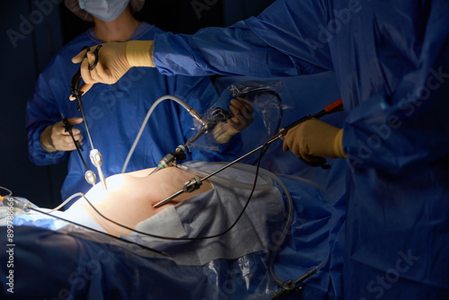 Surgeons holding an instrument in a patient abdomen in operation room