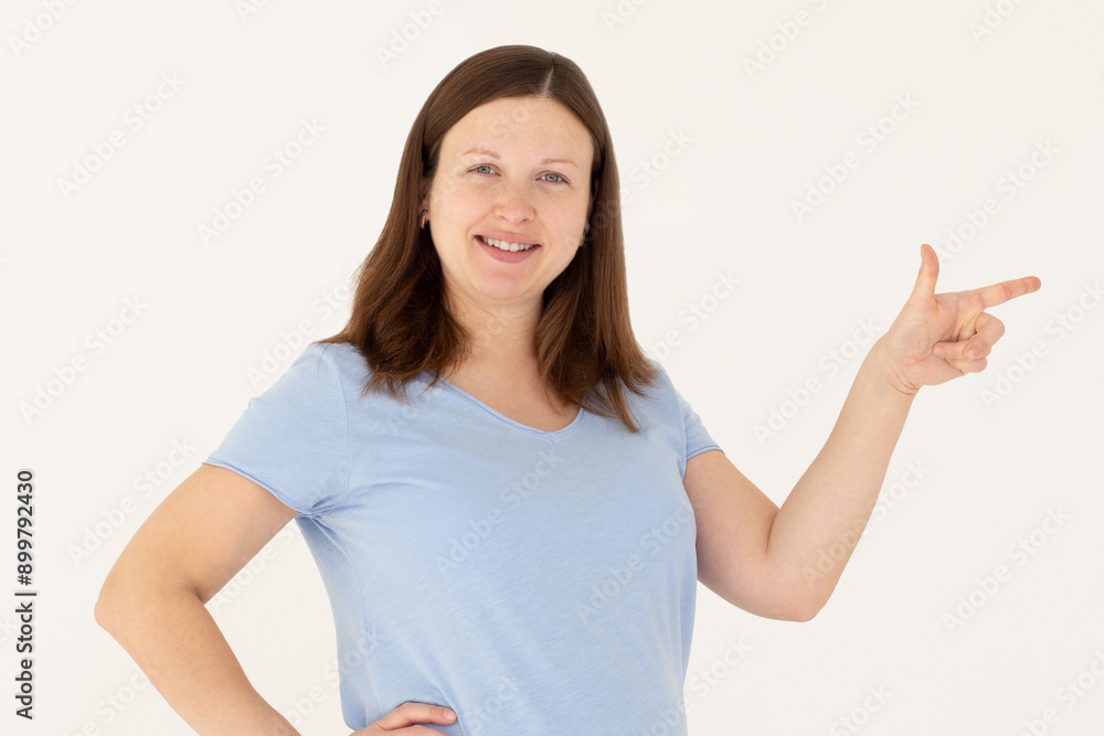 Hey look. Smiling pretty female model pointing finger right at empty space and inviting to check it out, showing advertisement on white background. Hey look. Smiling pretty female model pointing finger right at empty space and inviting to check it out, showing advertisement on white background.