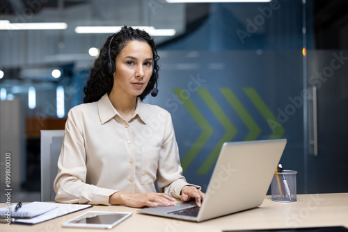 Customer service representative confidently working on laptop in modern office environment while wearing headset. Demonstrates professionalism, communication, and technology use in corporate setting.