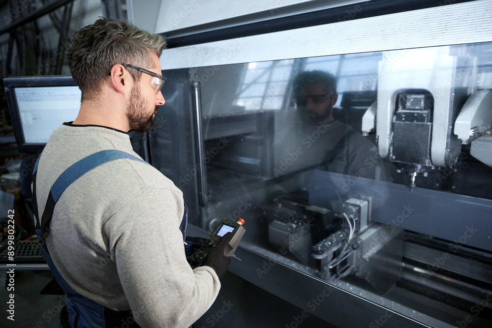 Employee uses a control panel to work on modern equipment Employee uses a control panel to work on modern equipment