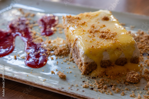 A dessert with a sauce and crumbs on served on a long plate with a raspberry sauce.