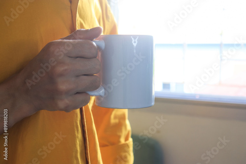 He is holding a white cup mockup in his hand
