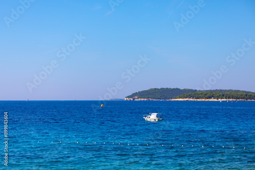 Beautiful seascape with blue sea and white boat in Croatia. Boat is floating in the sea with a yellow buoy in the water. The sky is clear and blue, and the water is calm