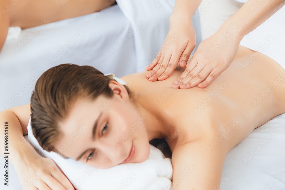 Caucasian couple customer enjoying relaxing anti-stress spa massage and pampering with beauty skin recreation leisure in day light ambient salon spa at luxury resort or hotel. Quiescent Caucasian couple customer enjoying relaxing anti-stress spa massage and pampering with beauty skin recreation leisure in day light ambient salon spa at luxury resort or hotel. Quiescent