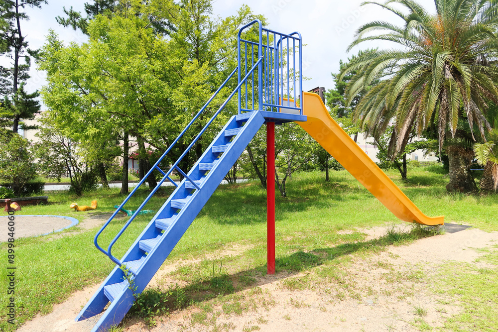 colourful slide with staircase taken in a park on a sunny day with grass field colourful slide with staircase taken in a park on a sunny day with grass field