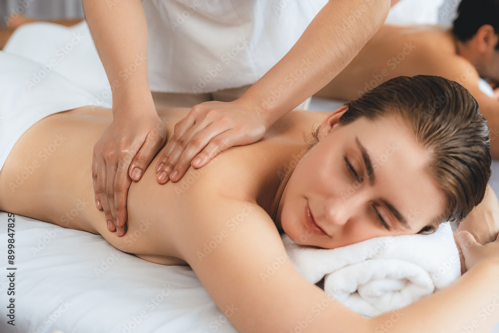 Caucasian couple customer enjoying relaxing anti-stress spa massage and pampering with beauty skin recreation leisure in day light ambient salon spa at luxury resort or hotel. Quiescent Caucasian couple customer enjoying relaxing anti-stress spa massage and pampering with beauty skin recreation leisure in day light ambient salon spa at luxury resort or hotel. Quiescent