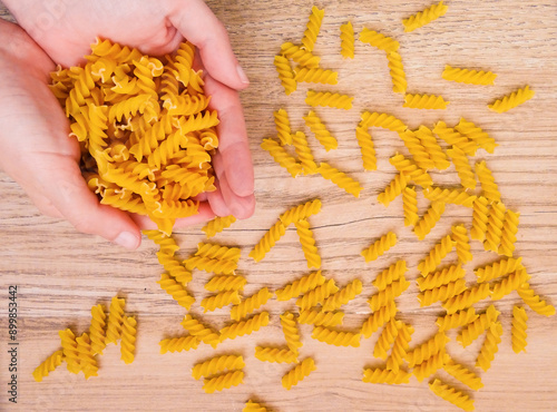 Close-up from above of hands holding uncooked fusilli macaroni pasta. Copy space