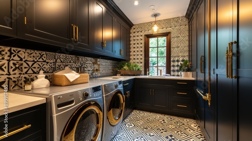 Dark and elegant laundry room featuring a patterned backsplash, black cabinets, and gold hardware. The room is equipped with modern appliances, ample storage, and decorative elements, creating a photo