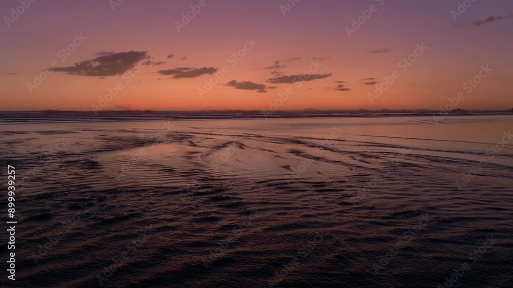 River estuary flowing over the sand into the ocean at sunset. Anawhata, Piha, Auckland, New Zealand. River estuary flowing over the sand into the ocean at sunset. Anawhata, Piha, Auckland, New Zealand.