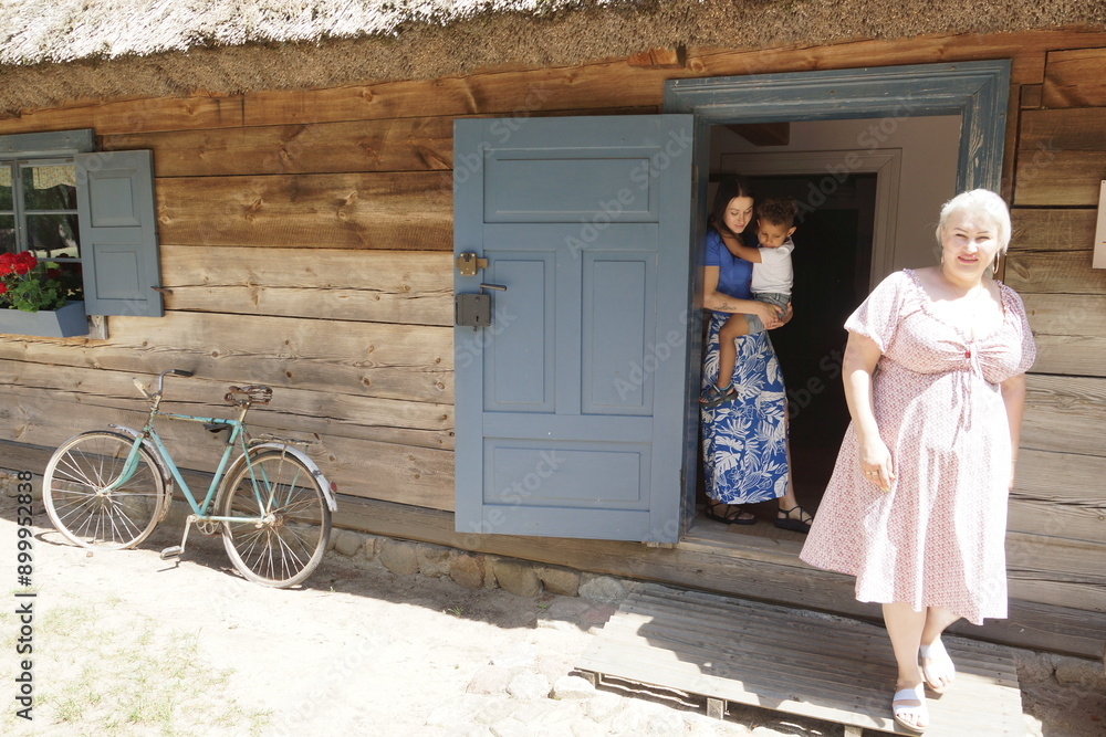 Rodzina przed domem. Mama dziecko i babcia.