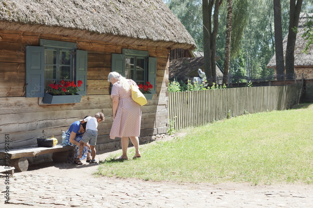 Rodzina. Mama ubierająca dziecko. Przed domem. Polska - Mazury - Warmia.