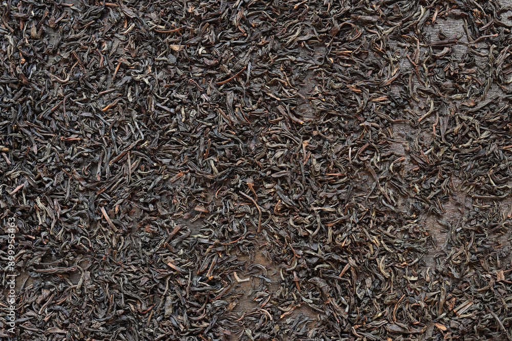 Long black tea on a dark wooden background. Top view of dried tea leaves. Tea composition. Ingredients for a hot drink, close-up Long black tea on a dark wooden background. Top view of dried tea leaves. Tea composition. Ingredients for a hot drink, close-up