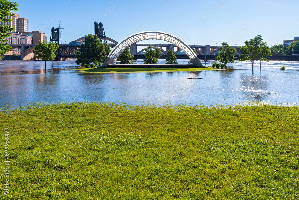 Fototapeta premium part of raspberry island regional park submerged under mississippi river floodwaters with bandshell visible and robert street bridge behind it