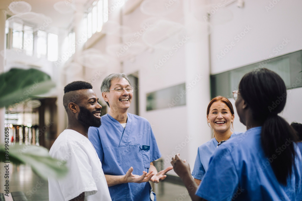 Happy male and female medical professionals enjoying while talking with each other in hospital lobby Happy male and female medical professionals enjoying while talking with each other in hospital lobby