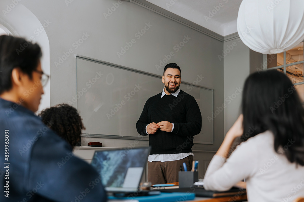 Smiling businessman discussing strategies with colleagues in meeting at office Smiling businessman discussing strategies with colleagues in meeting at office