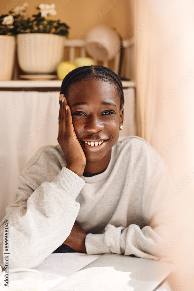 Happy teenage boy sitting with book on table at home Happy teenage boy sitting with book on table at home