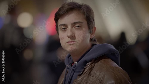 A young individual is seen sporting a stylish brown leather jacket against an urban backdrop