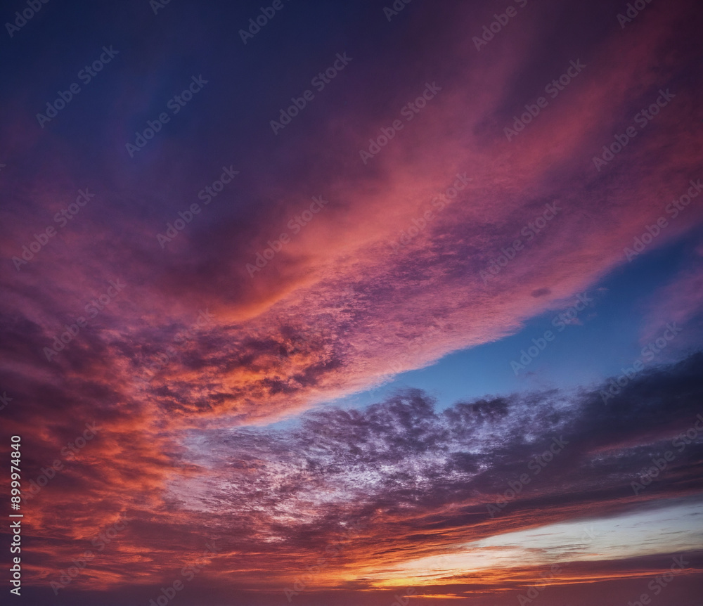 Fototapeta premium Dramatischer Sonnenuntergang mit intensiven Farben und Wolkenformationen, die den Himmel in ein faszinierendes Farbspiel aus tiefem Blau, kräftigem Rosa und leuchtendem Orange tauchen