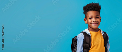 Portrait of happy black schoolboy on isolated blue background 