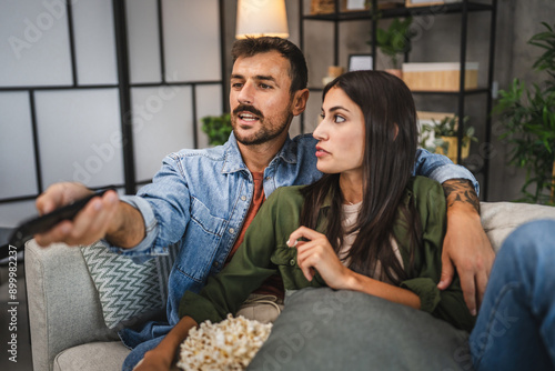 adult couple watch movie, series on television and eat popcorn at home