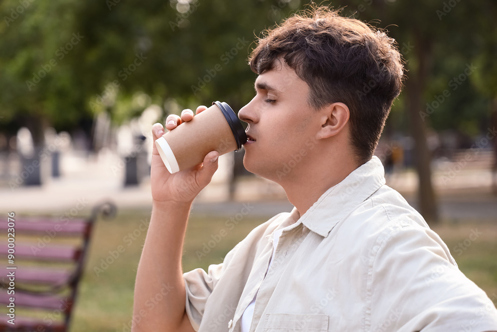 Obraz premium Handsome young man drinking delicious latte outdoors