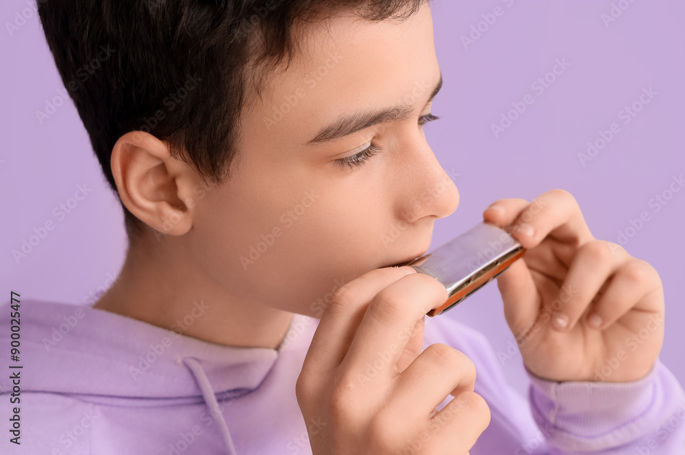 Teenage boy playing harmonica on lilac background, closeup Teenage boy playing harmonica on lilac background, closeup