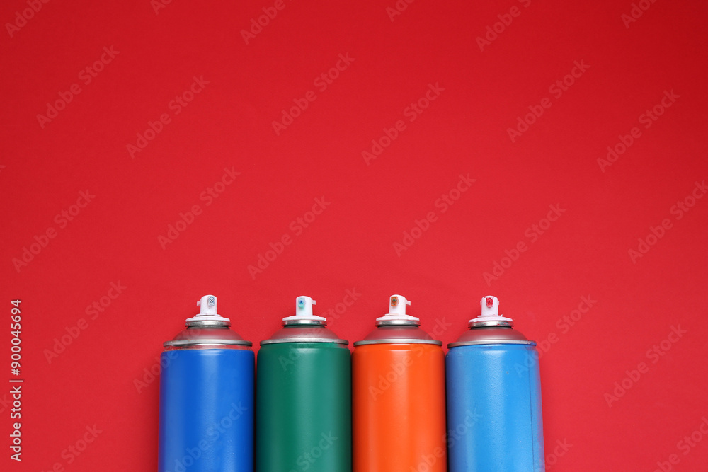 Many spray paint cans on red background, top view. Space for text Many spray paint cans on red background, top view. Space for text