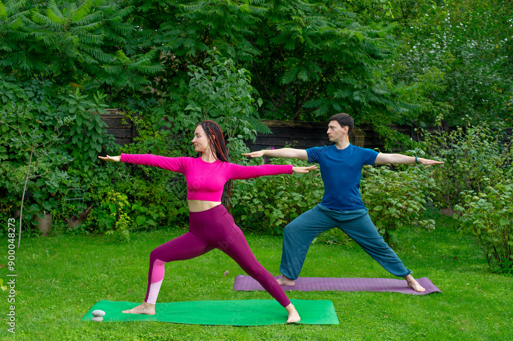 couple meditating doing yoga in nature.man and woman doing yoga exercises meditating on green grass couple meditating doing yoga in nature.man and woman doing yoga exercises meditating on green grass
