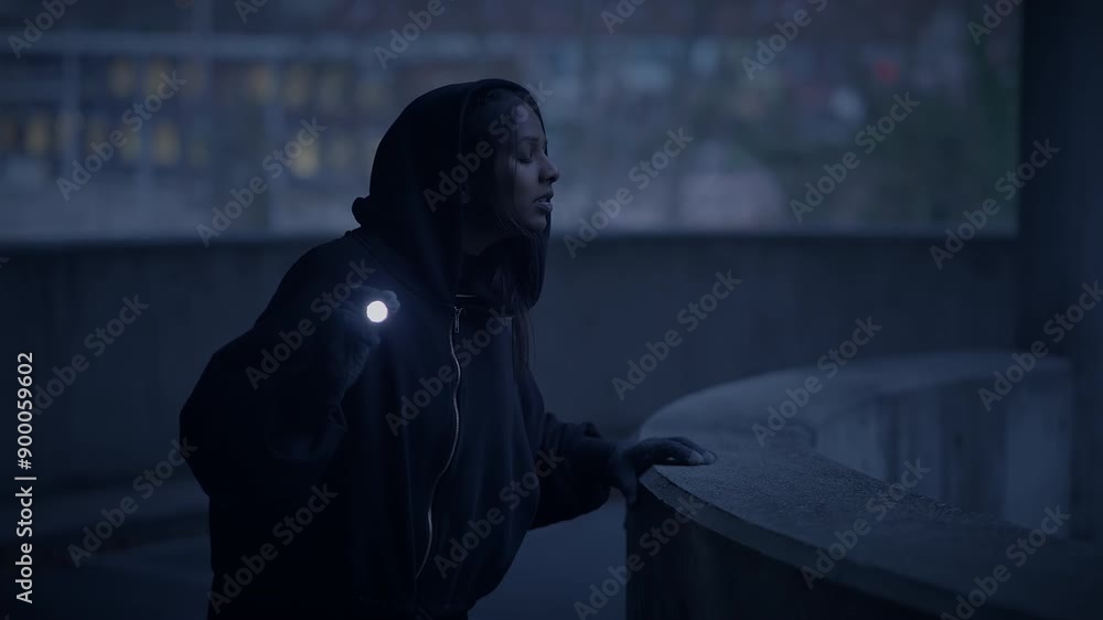 Person in a hoodie gazing at city outskirts, evoking solitude and tranquility on a calm night Person in a hoodie gazing at city outskirts, evoking solitude and tranquility on a calm night