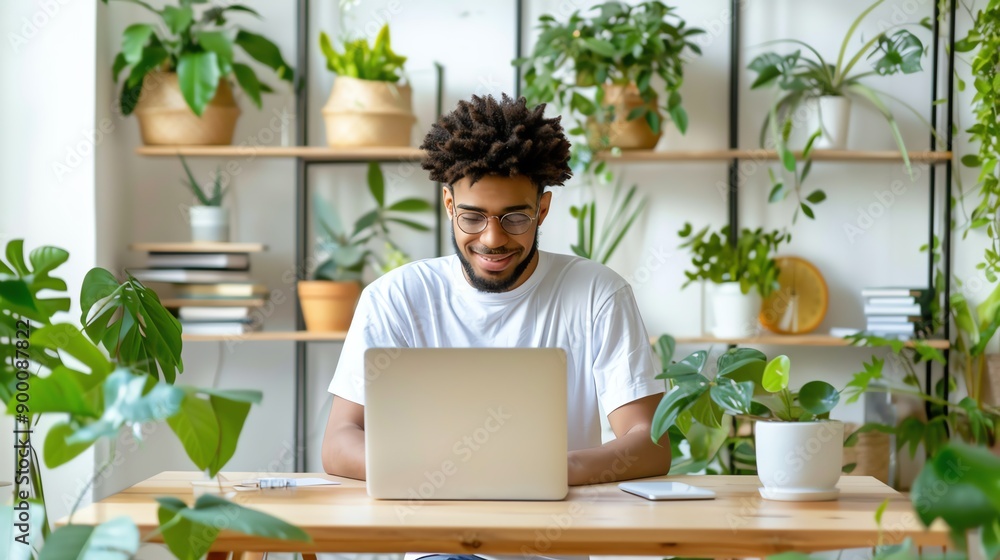 A young man working on a laptop surrounded by indoor plants, showcasing a modern and relaxed workspace. A young man working on a laptop surrounded by indoor plants, showcasing a modern and relaxed workspace.