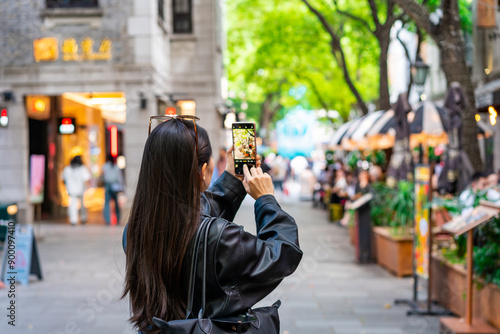 Young female tourist taking a photo of the Xintiandi shopping street landmark and popular attractions in Shanghai, China