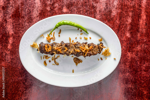 Beef seekh kabab with fried onion served in plate isolated on table background top view of bangladeshi, indian and pakistani food photo