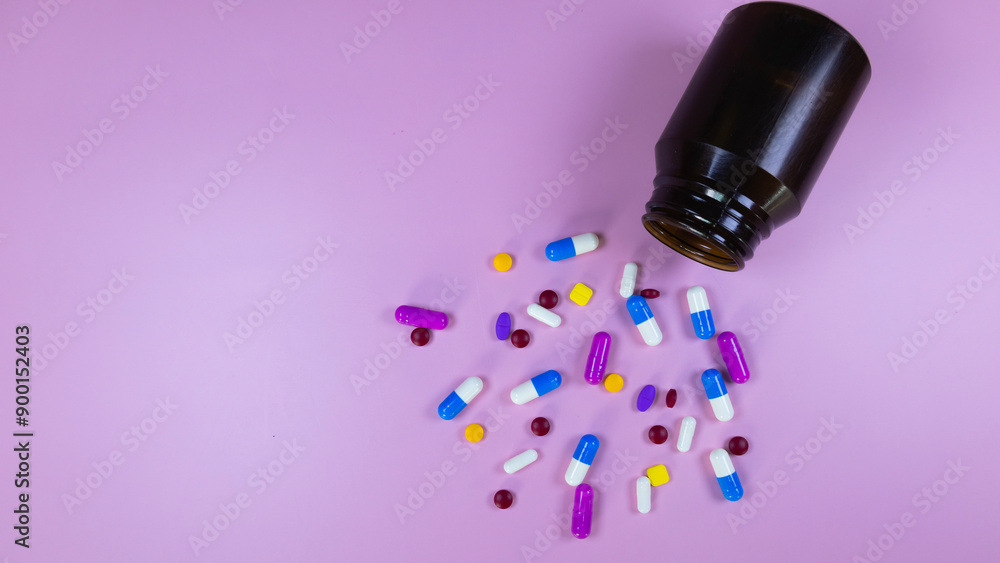 Multi-colored pills, capsules used in medical treatment are scattered on a pink background. Colorful pills, capsules and brown medicine bottle. Healthcare and medical concept. Space for text. Multi-colored pills, capsules used in medical treatment are scattered on a pink background. Colorful pills, capsules and brown medicine bottle. Healthcare and medical concept. Space for text.