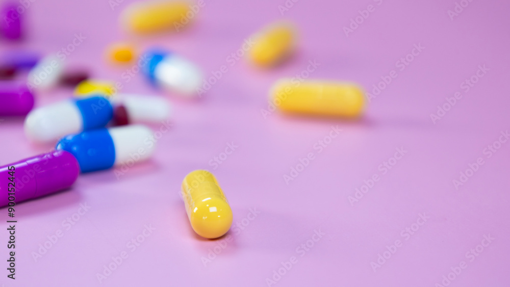 Multi-colored pills and capsules used in medical treatment are scattered on a pink background. Colorful pills and capsules. Healthcare and medical concept. Space for text. Multi-colored pills and capsules used in medical treatment are scattered on a pink background. Colorful pills and capsules. Healthcare and medical concept. Space for text.