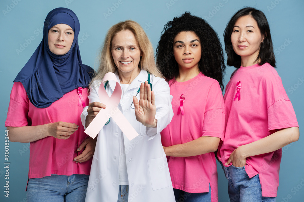 Doctor and women united against breast cancer with pink ribbon showing stop sign looking at camera Doctor and women united against breast cancer with pink ribbon showing stop sign looking at camera