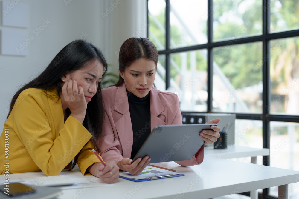 Asian businesswoman who is working hard and stressed Headache over financial paperwork with co-workers while sitting at desk in office, Office Syndrome concept. Asian businesswoman who is working hard and stressed Headache over financial paperwork with co-workers while sitting at desk in office, Office Syndrome concept.