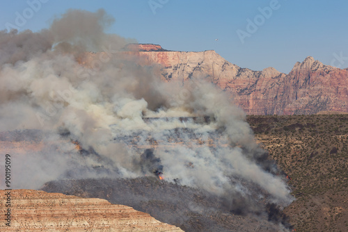 Clouds of smoke billow up partly hiding the cliffs of West Temple Mountain in Zion Nat. Park, Utah, USA while patches of flame consume the brush growing along the steep hillside above Virgin Utah.