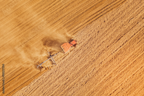 Aerial view of a tractor harvesting wheat in a vast field, showcasing agriculture beauty
