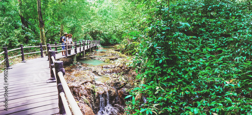 Asian Lover happy travel the mangrove forest. She is walking on a wooden bridge. Nature trail, Thanbok waterfall, recreation, travel, backpacks, nature, tourism, countryside, style, forest, adventure. photo