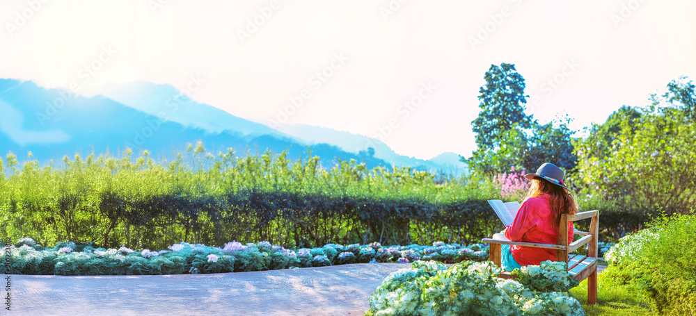 Fototapeta premium Asian woman travel nature. Travel relax. Read the book on the bench in the park in summer.