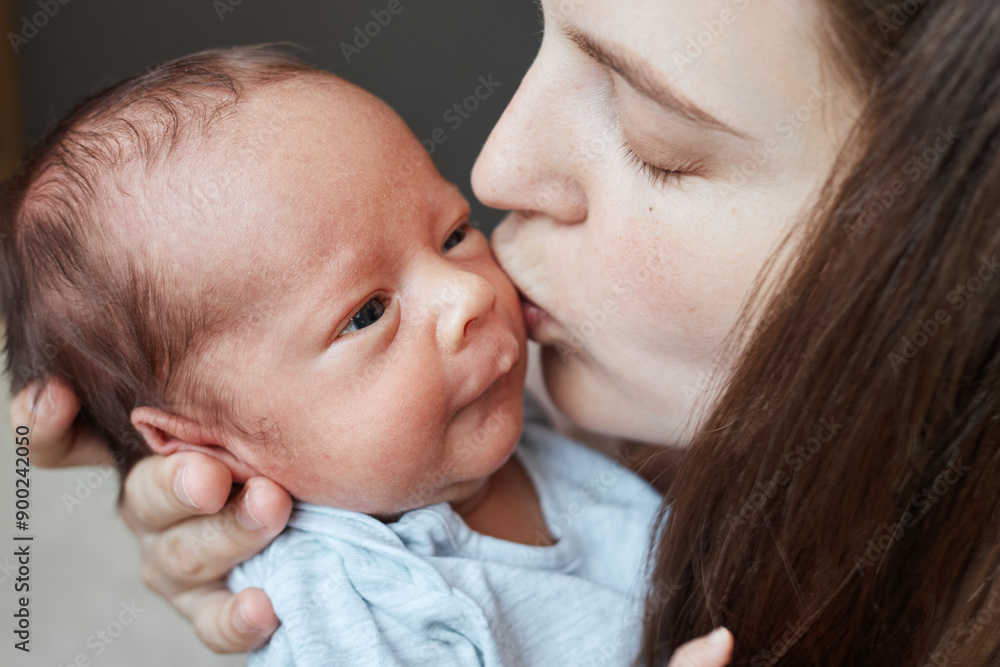 Loving mama gently holding her new baby expressing happiness and love that comes with welcoming little boy into the family mother kissing tiny infant son or daughter Loving mama gently holding her new baby expressing happiness and love that comes with welcoming little boy into the family mother kissing tiny infant son or daughter