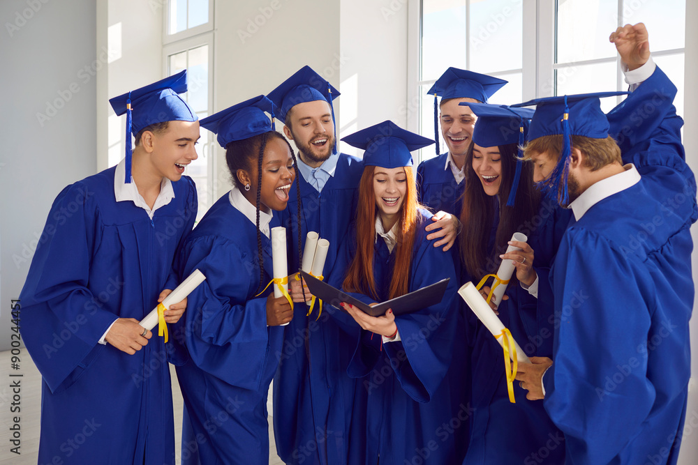Portrait of a group of smiling excited happy diverse graduates students talking and having fun in a university graduate gown and holding diploma indoors. Education and graduation concept. Portrait of a group of smiling excited happy diverse graduates students talking and having fun in a university graduate gown and holding diploma indoors. Education and graduation concept.