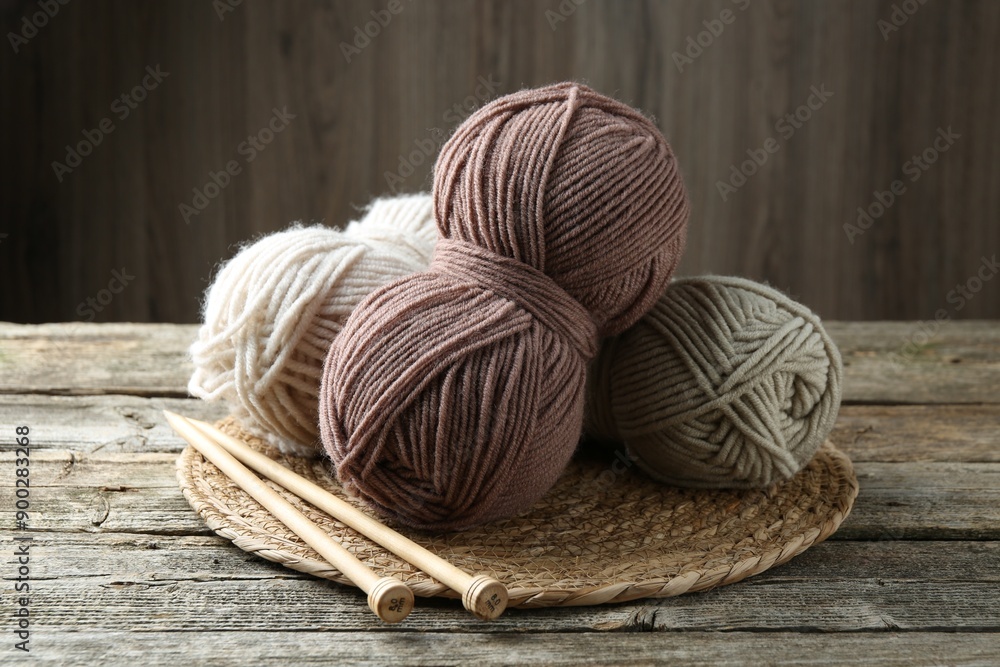Skeins of yarn, knitting needles and wicker mat on wooden table, closeup Skeins of yarn, knitting needles and wicker mat on wooden table, closeup