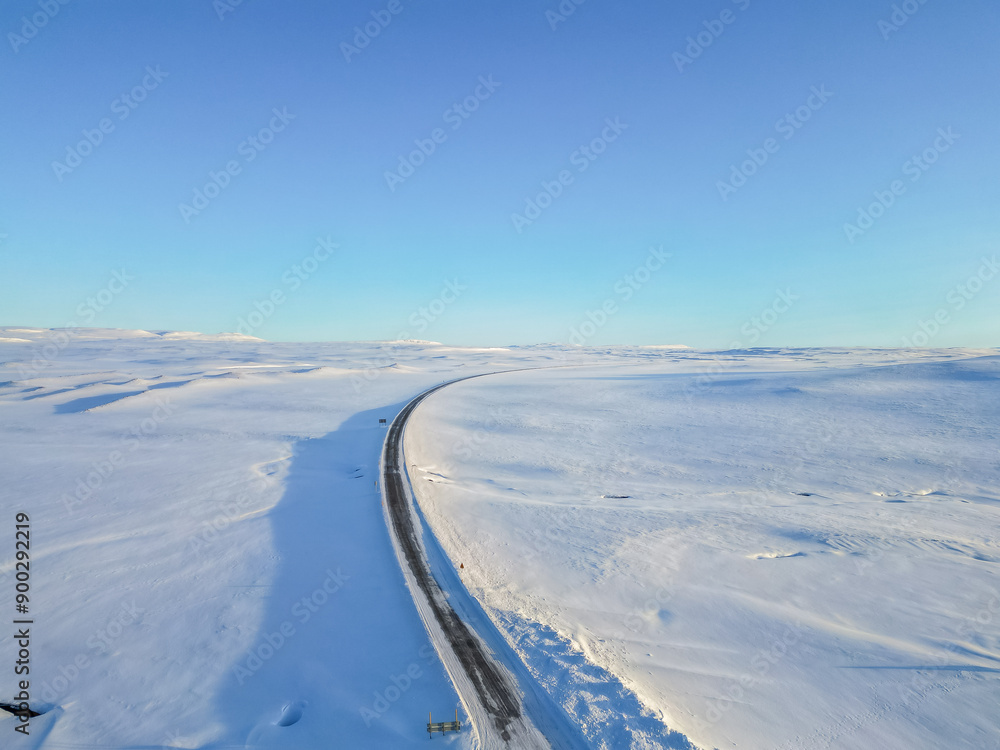 Beautiful aerial drone view landscape. Frozen road in winter in Iceland. Snowy roadsides during winter with blue sky. Beautiful aerial drone view landscape. Frozen road in winter in Iceland. Snowy roadsides during winter with blue sky.