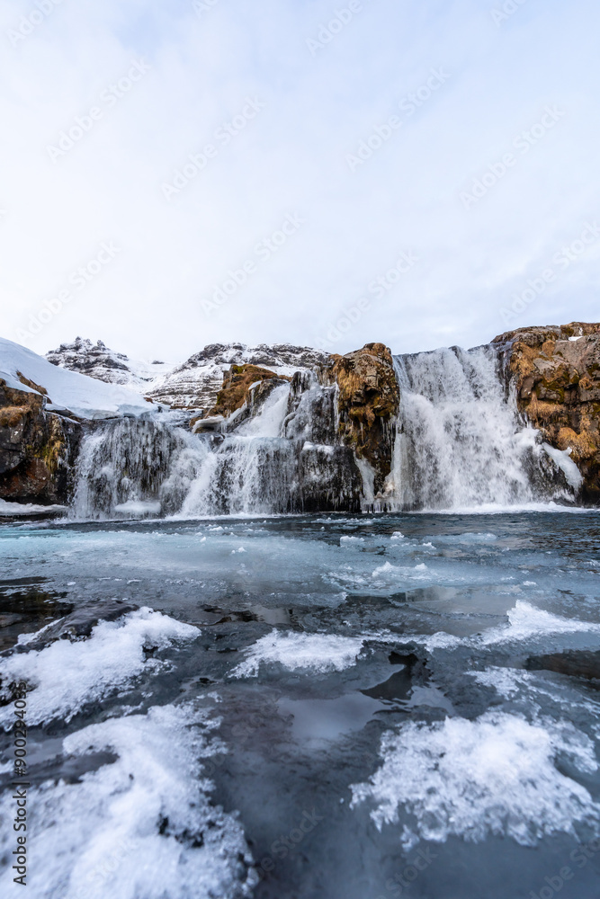 Frozen water in the waterfall next to the famous Kirkjufell mountain in winter in Iceland Frozen water in the waterfall next to the famous Kirkjufell mountain in winter in Iceland