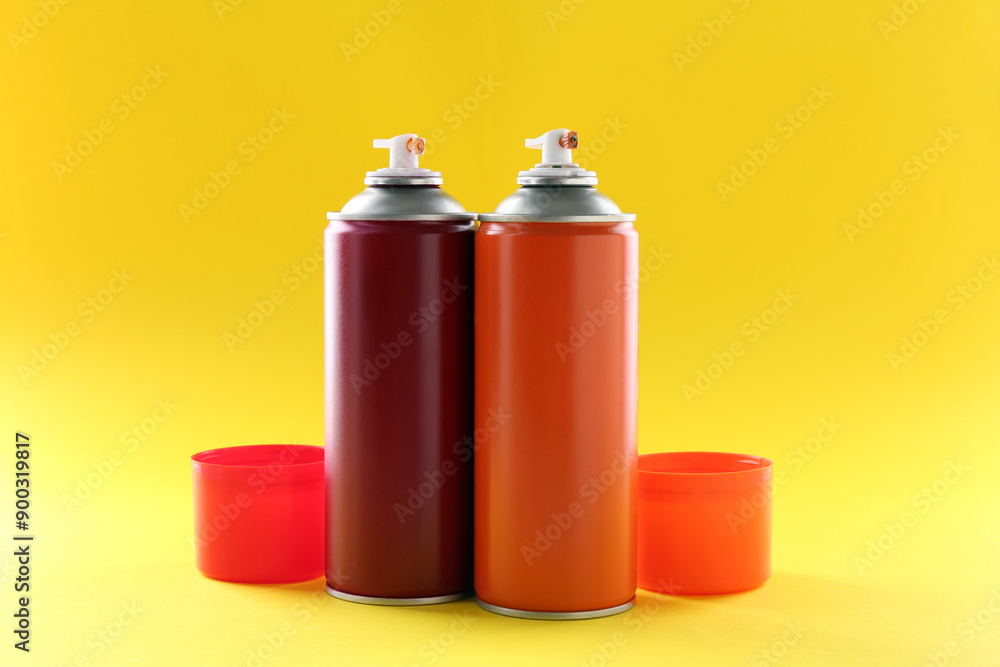 Two spray paint cans on yellow background Two spray paint cans on yellow background