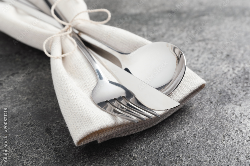 Stylish silver cutlery and napkin on grey table, closeup Stylish silver cutlery and napkin on grey table, closeup