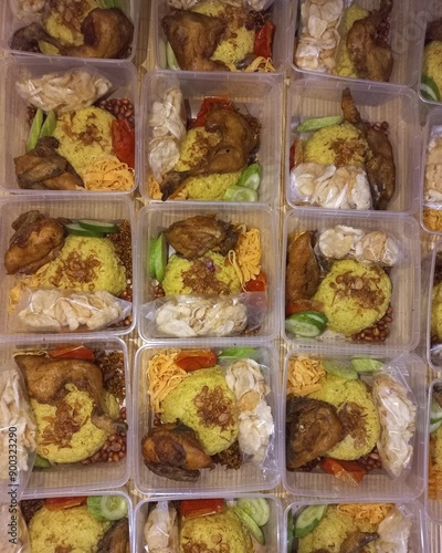 Traditional food called nasi kuning Indonesian culinary service with egg slices, chicken fried, tempeh, nuts, cucumber, and emping chip | Natural photos photo