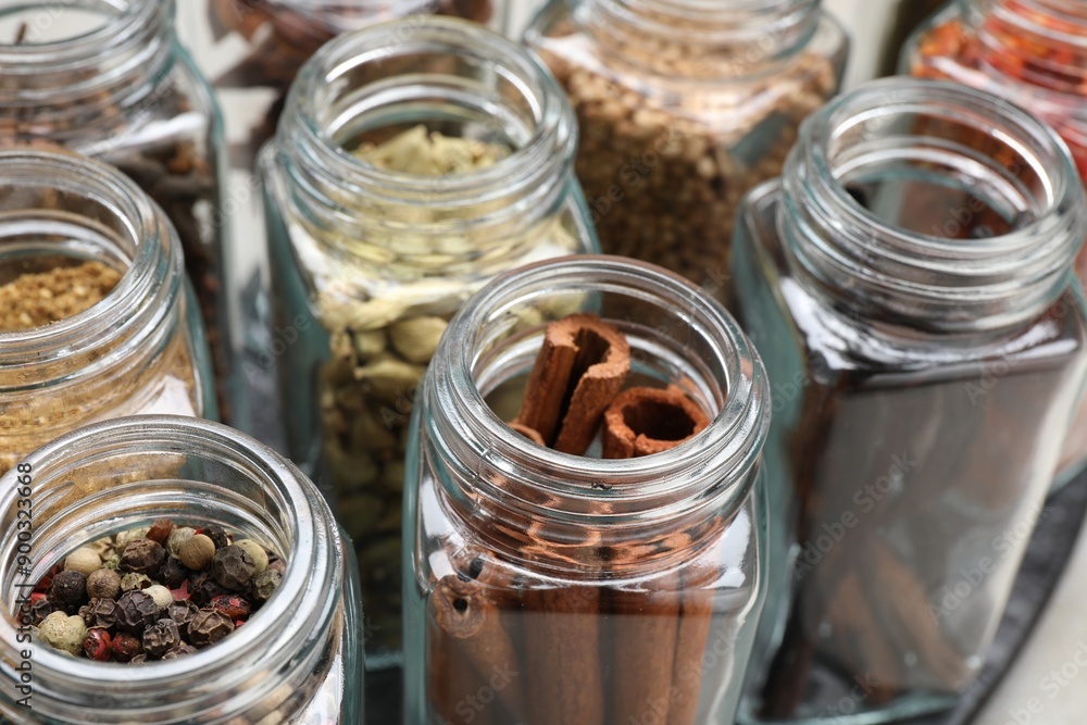 Different spices in glass jars on table, closeup Different spices in glass jars on table, closeup