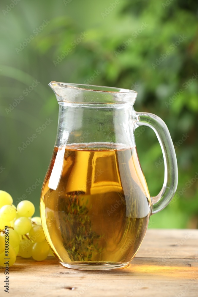 Tasty juice in glass jug and grapes on wooden table outdoors Tasty juice in glass jug and grapes on wooden table outdoors